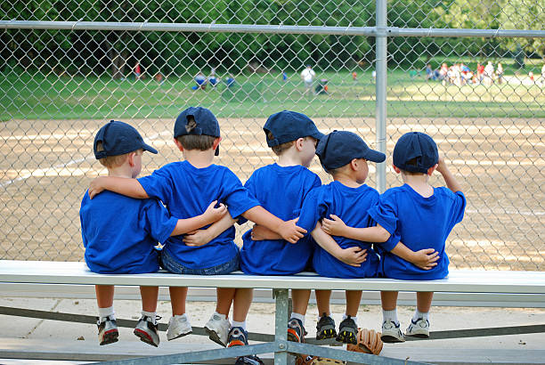 five little boys put their arms around each other befor their baseball game